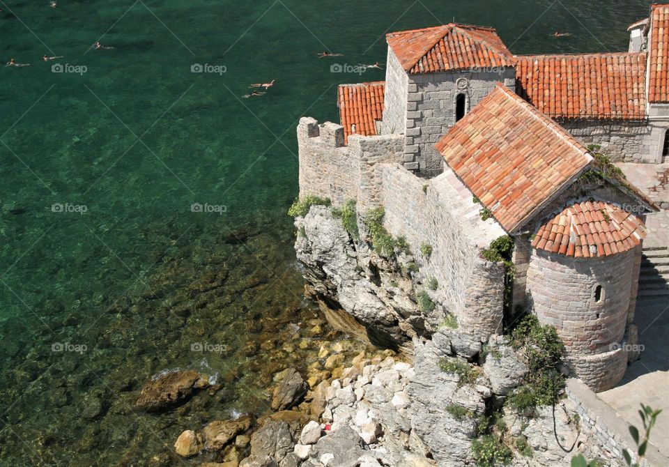 Swimming in clear waters of Adriatic Sea around an old building 