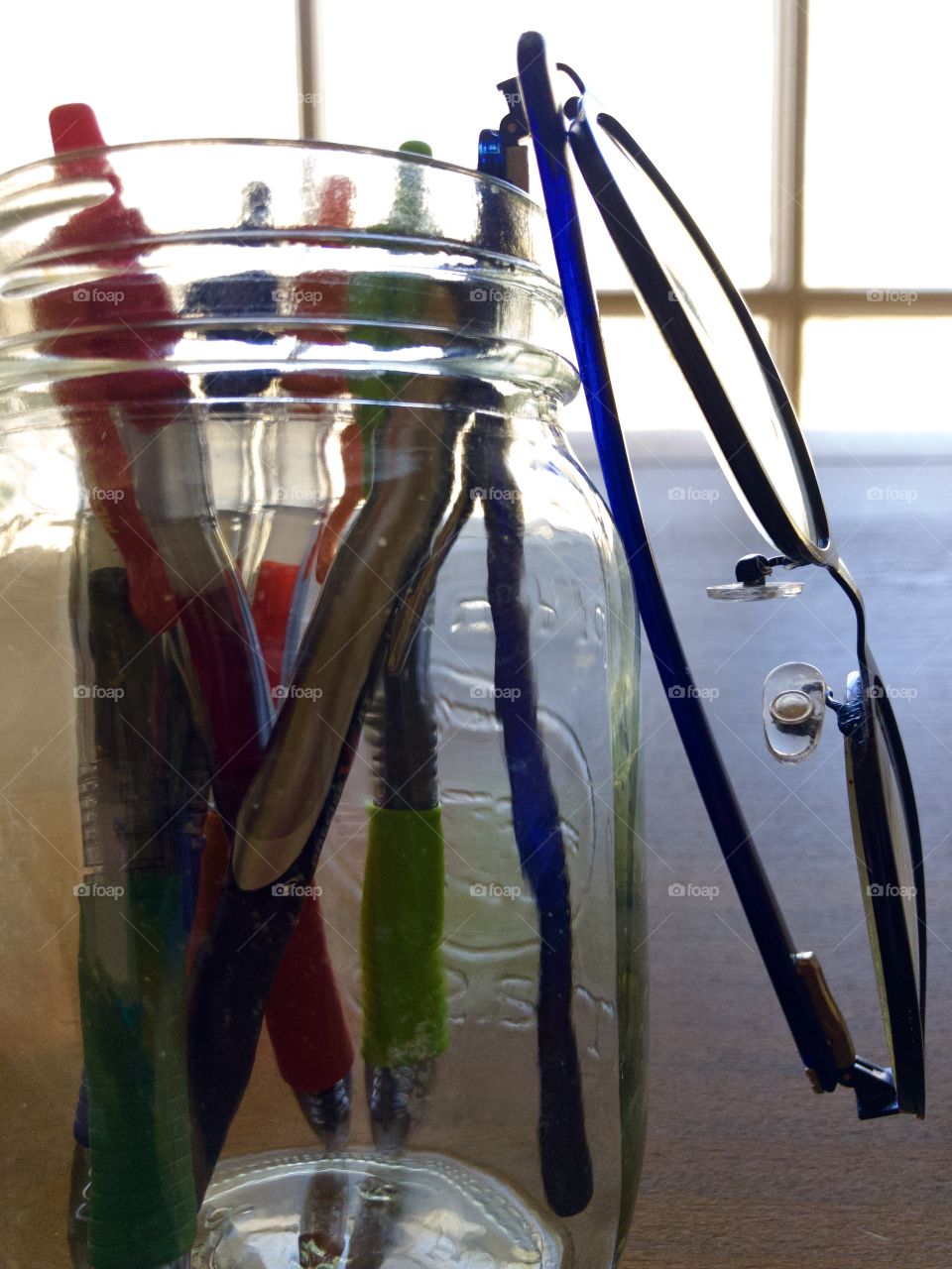 Mason jar holding pens and pair of reading glasses 