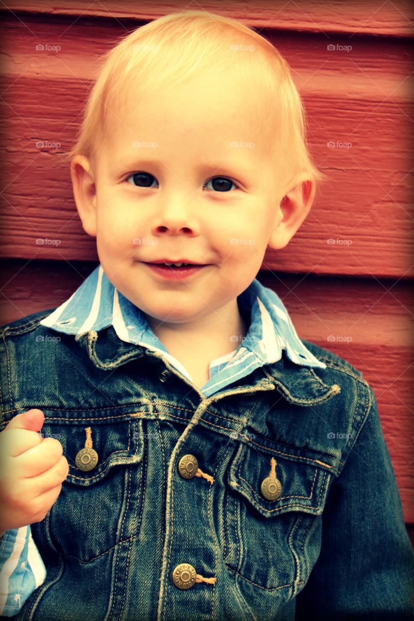 Boy standing near wooden wall