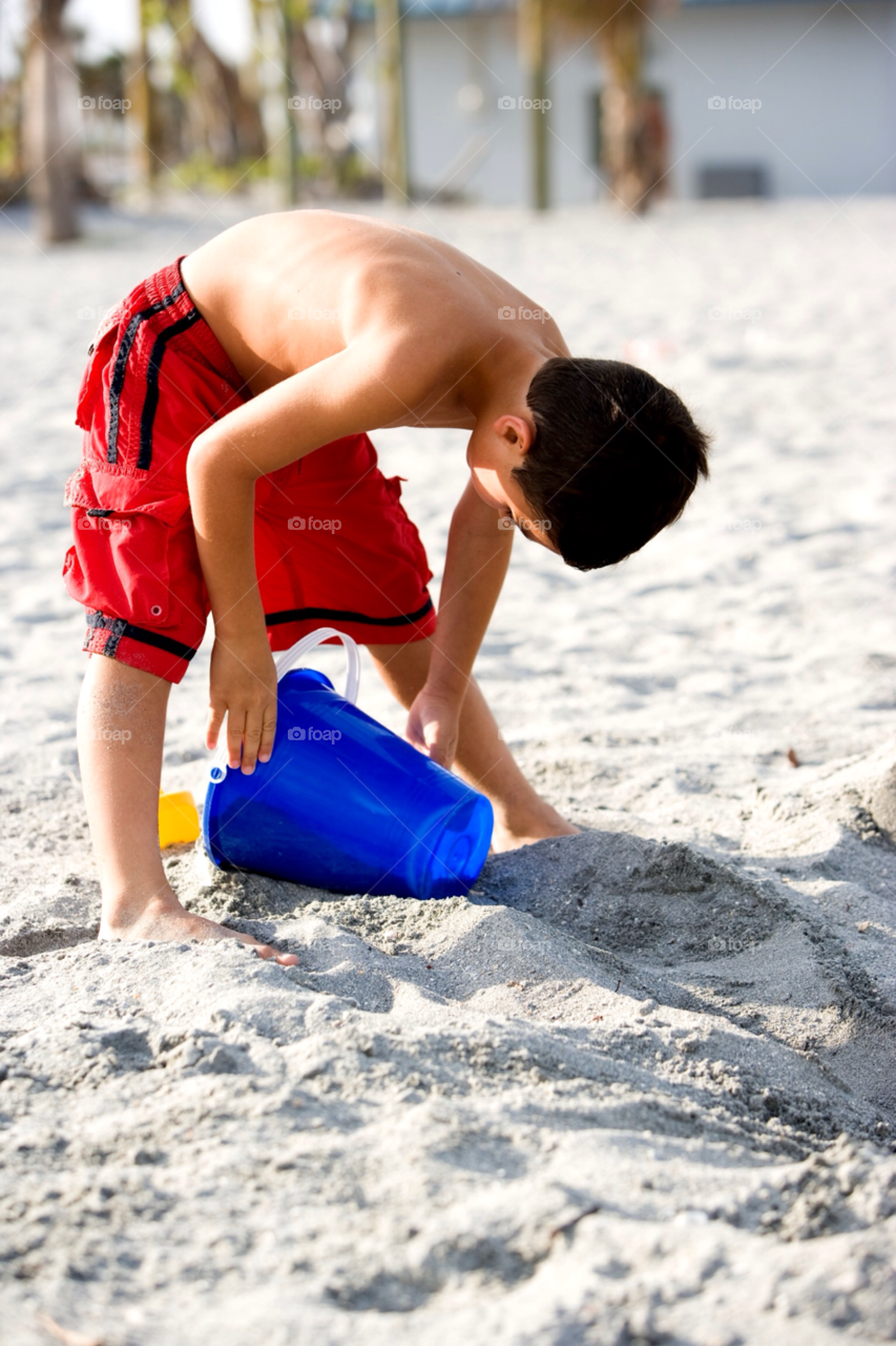 Young boy playing with sand on the beach, Hollywood Beach,  Florida, USA 
