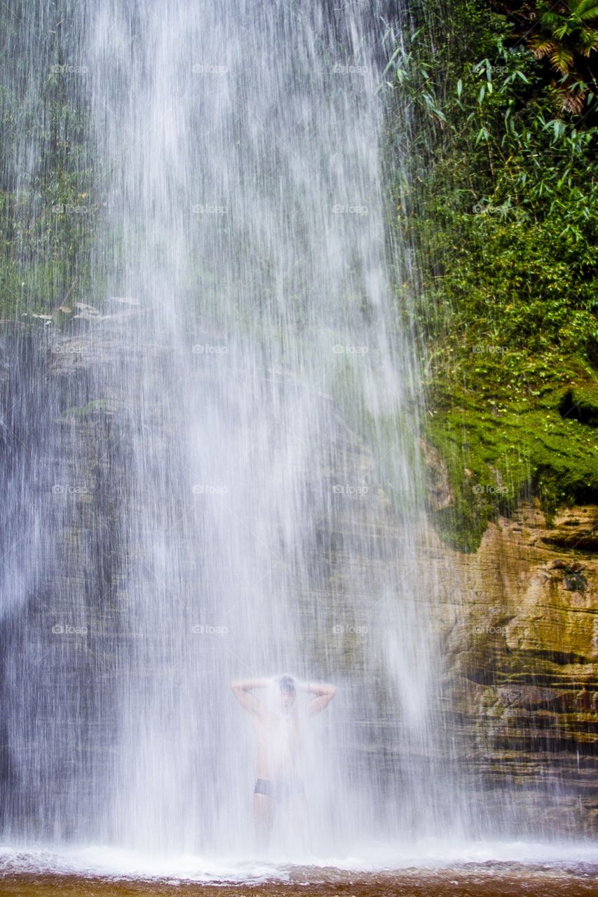 Strong shower. A men showering in the strong and cold waters from the fall, in Ibitipoca national park, Minas Gerais, Brazil 