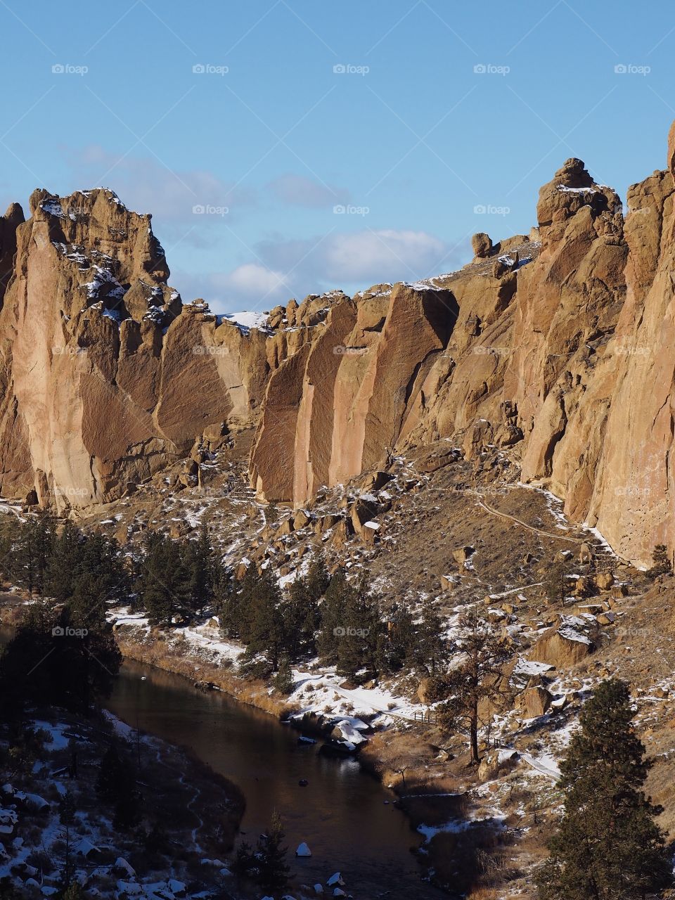 The Crooked River in Central Oregon flows through Smith Rocks State Park with a layer of snow on a sunny winter day. 