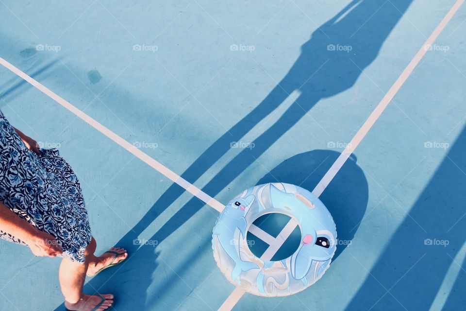 Persons shadow on blue sports field in sunlight