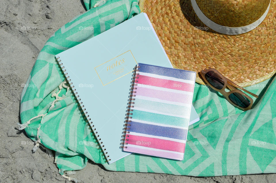 Notebook and planner laid out on the beach