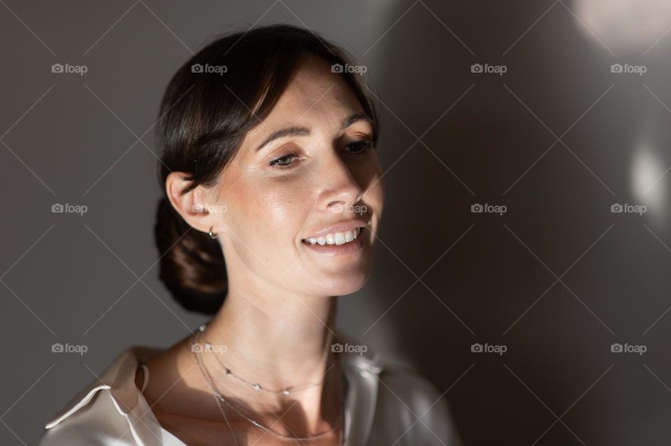 A calm smiling woman standing against a gray wall