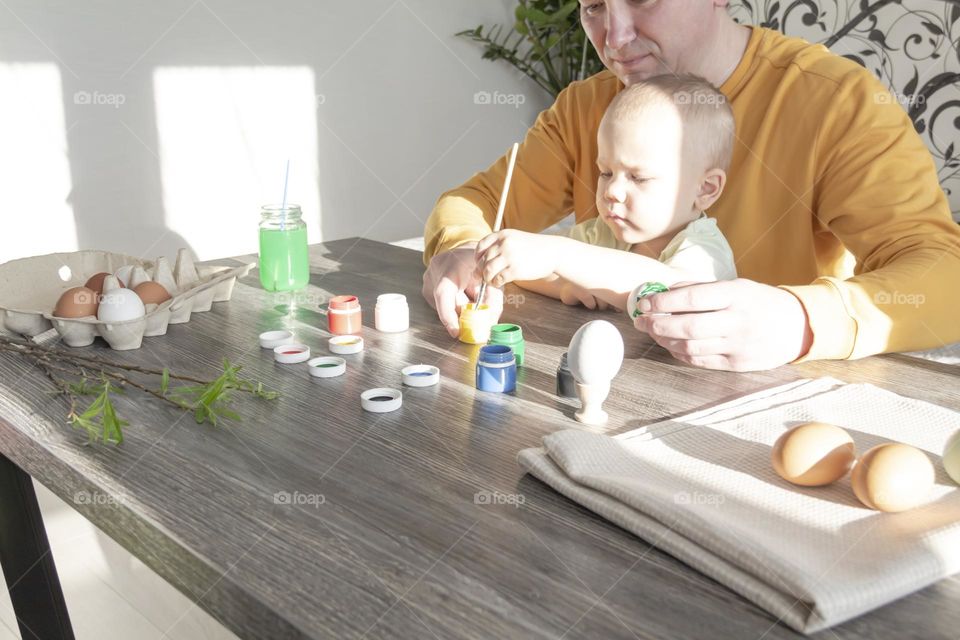 dad with a little son draw with paints at a wooden table