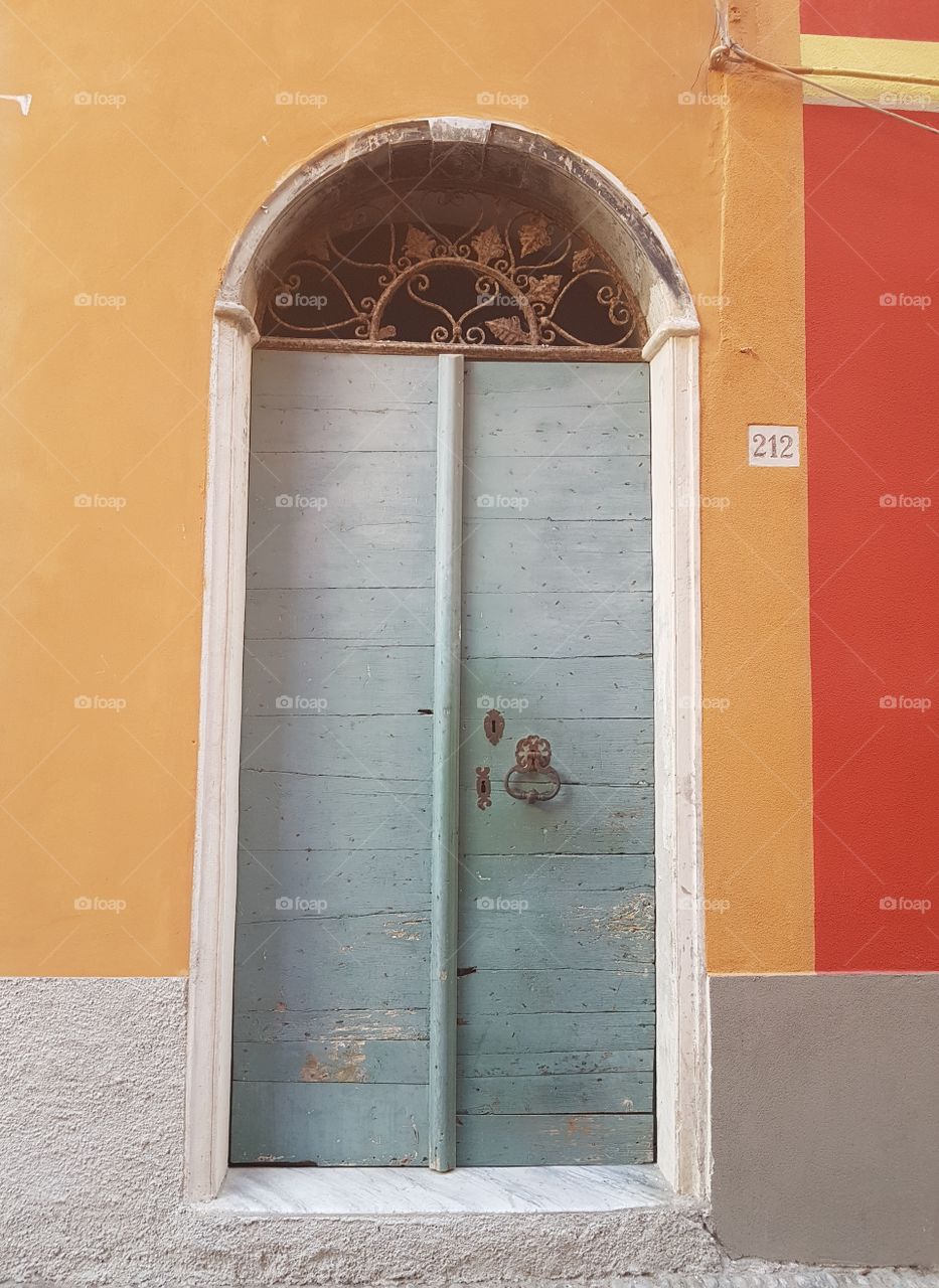 Antique entrance door of a
italian house with multicolored walls