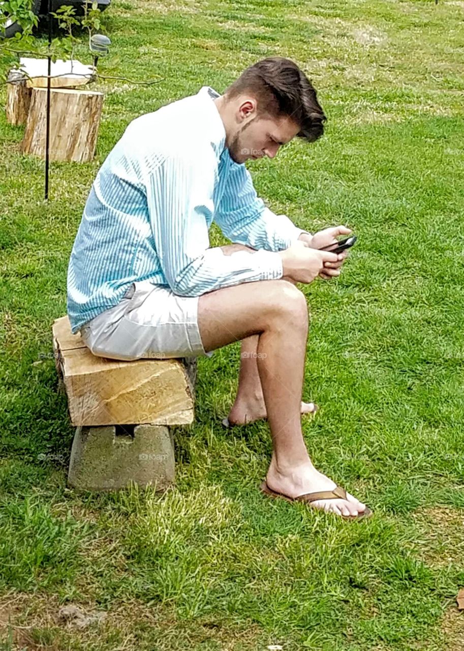 man relaxing checking messages on cellphone