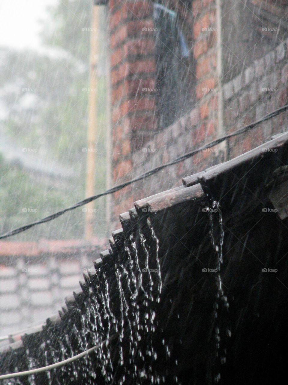 Close-up view of the roof of a house being flooded by heavy rainwater