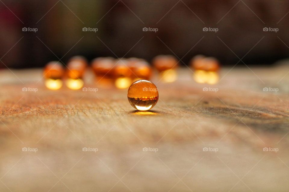 a beautiful image of translucent balls rolled across the floor. small pills with fish oil on a wooden surface.  in the center one ball