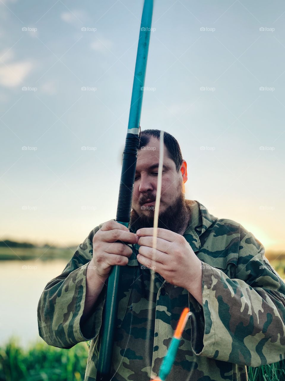 Bearded guy is fishing on the lake