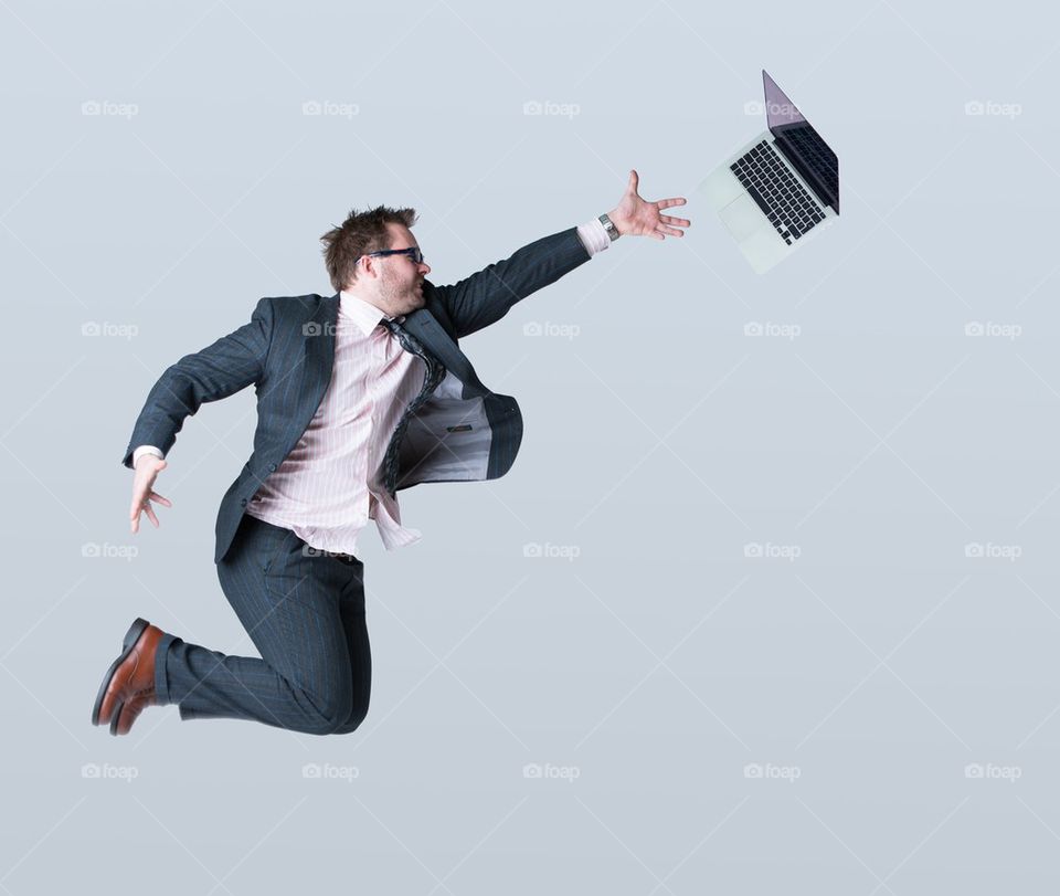 Young businessman and laptop against grey background