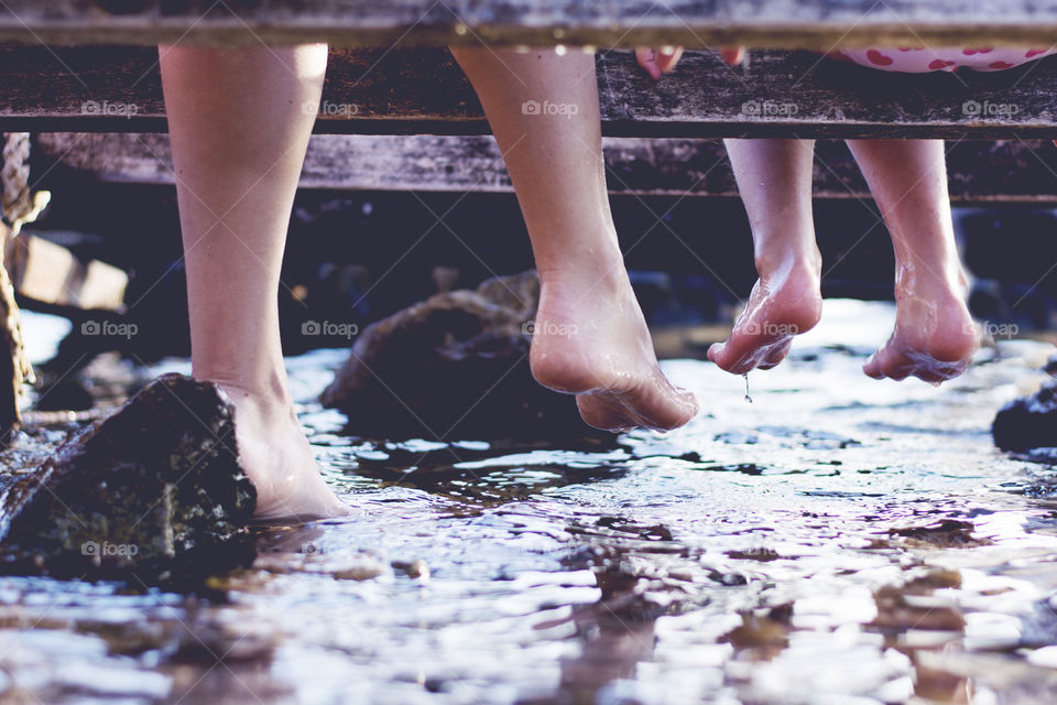 mother and daughter barefoot. mother and daughter bare feet sitting on a deck with feet above water