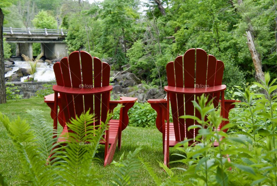 Two Muskoka chairs resting by the river.