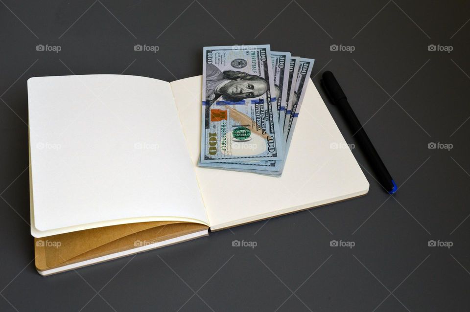 Dollars on the table with a notebook