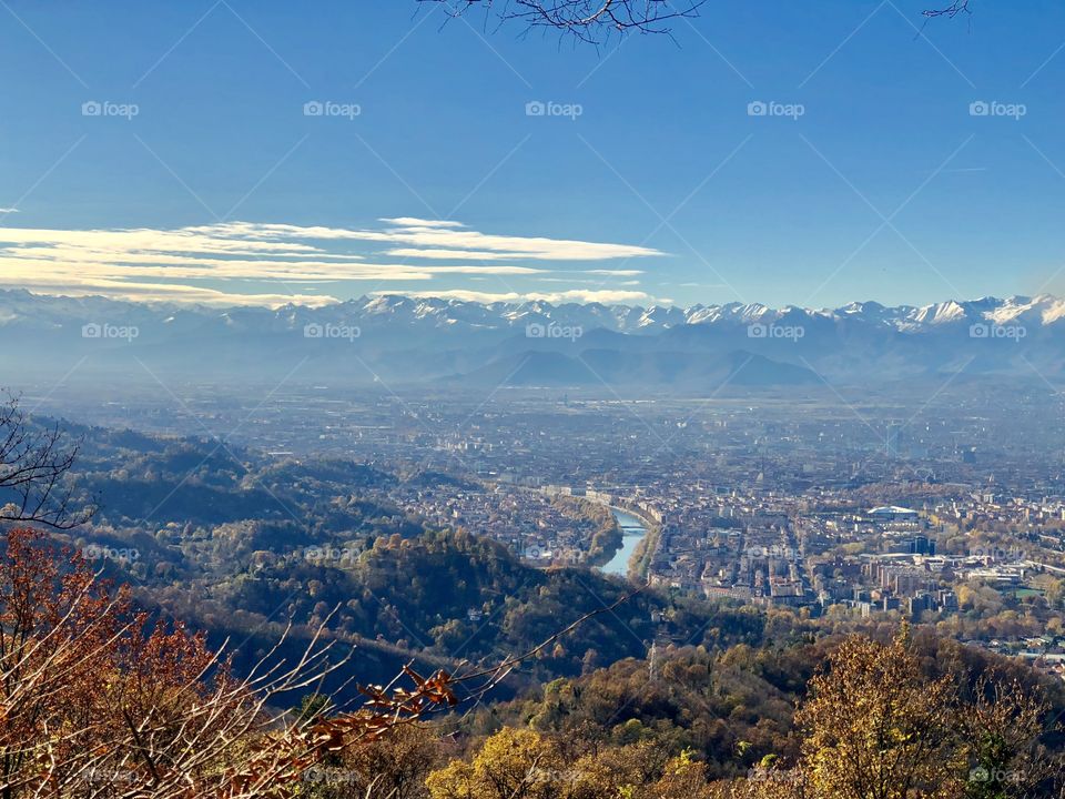 View of a city from the top of a mountain with the alps on the back