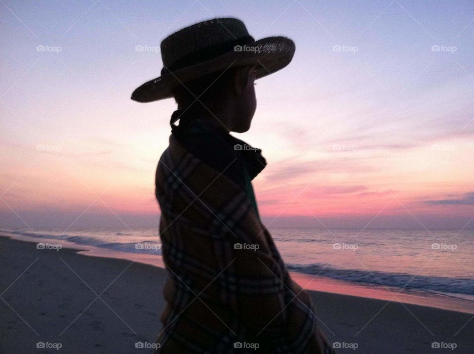 Beautiful Boy siloutte watching a sunrise on the beach