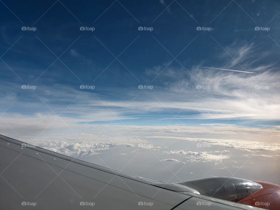 airplane wing and flying above the clouds blue sky white clouds 