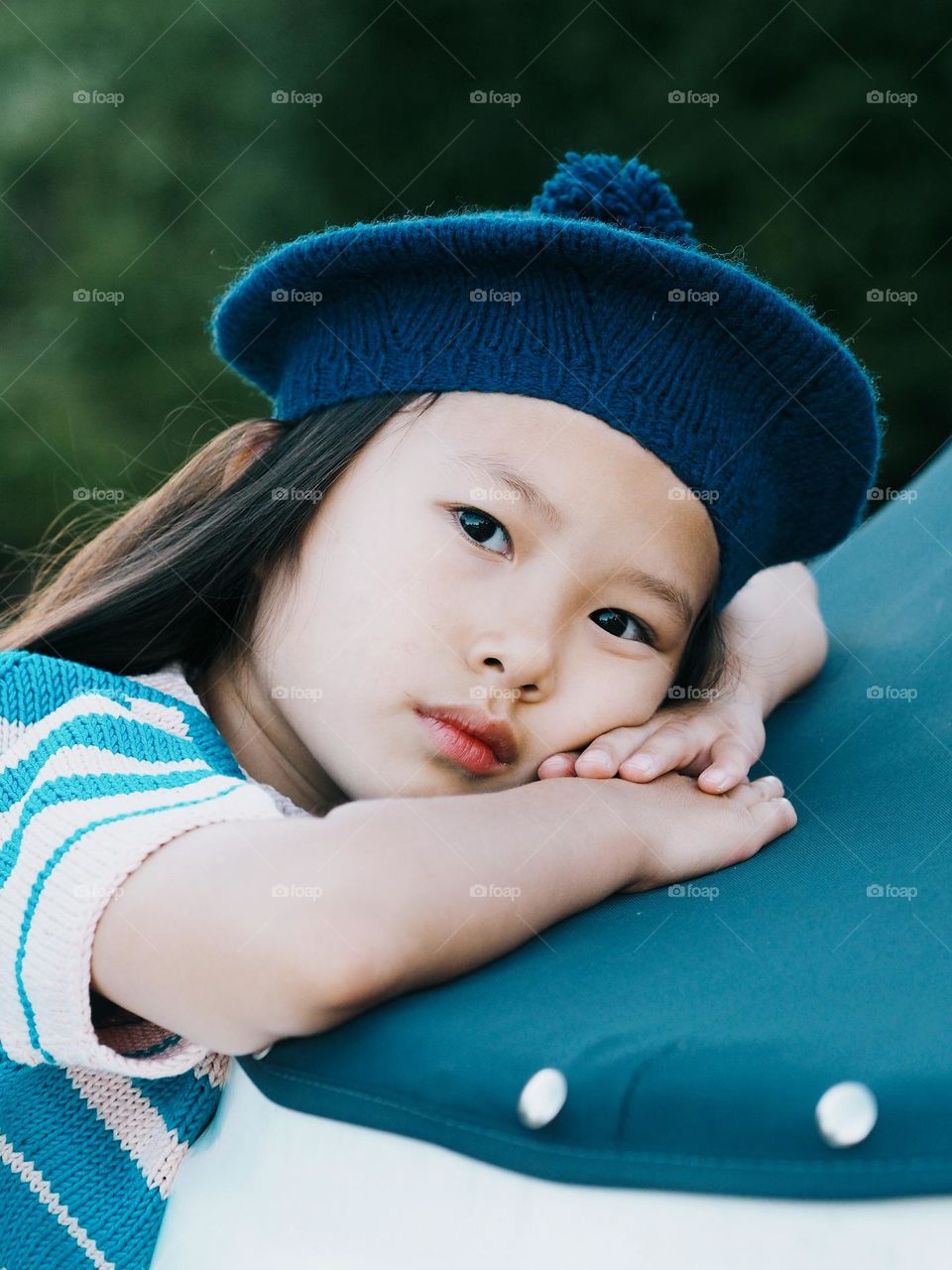 Portrait of cute little serious asian girl wearing striped shirt and blue beret, portrait of child, looking at camera.