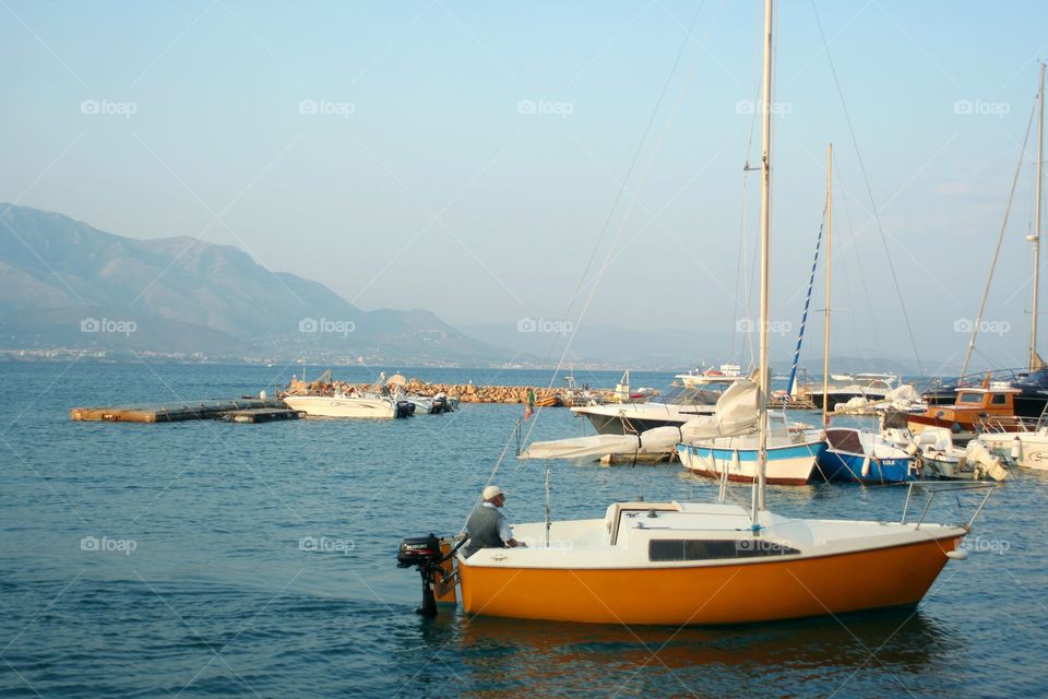 Old man on boat returns in harbor at evening