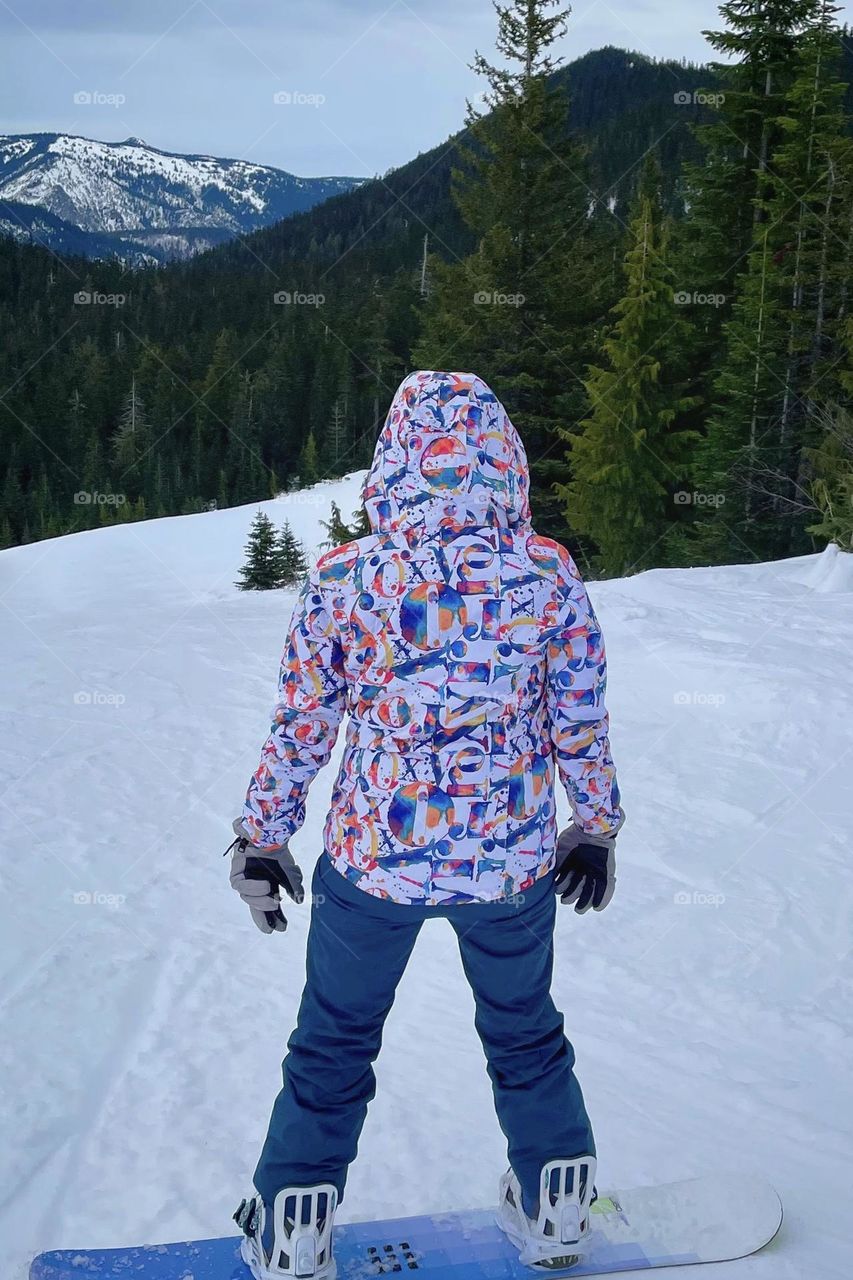 A colorfully dressed snowboarder prepares to move down a slope at White Pass Ski Resort in Washington State