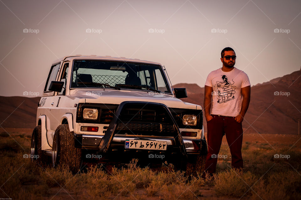 offroad style. a handsome guy with his pimped Patrol looking for offroad adventures in desert at sunset with his stylish sunglasses.