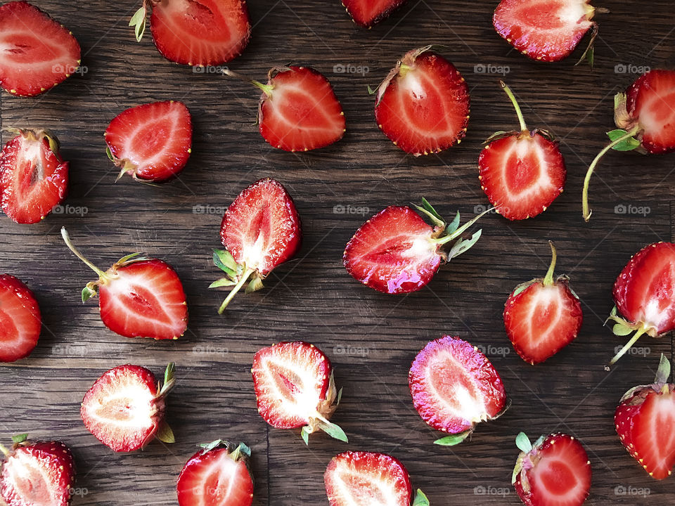 Halves of red strawberries on wooden background 