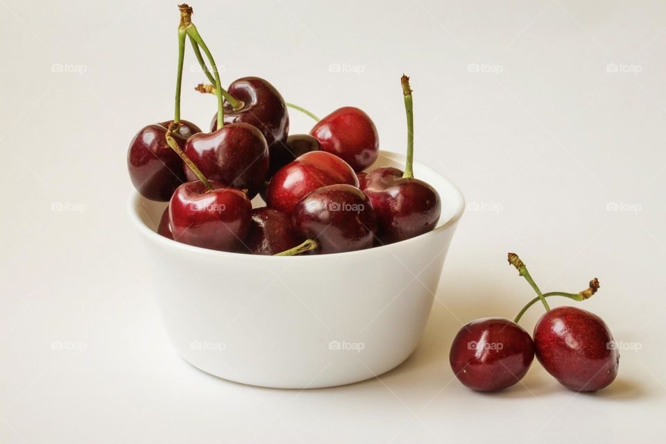 Delicious cherries in white bawl on white background