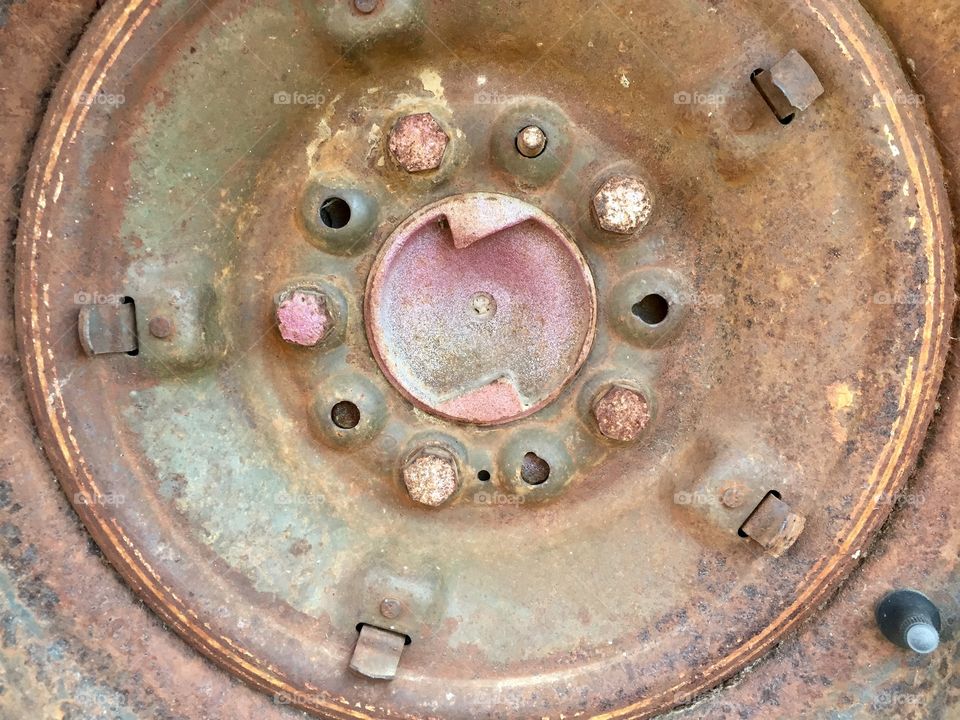 Closeup of a rusted rim and lug bolts on a vintage vehicle