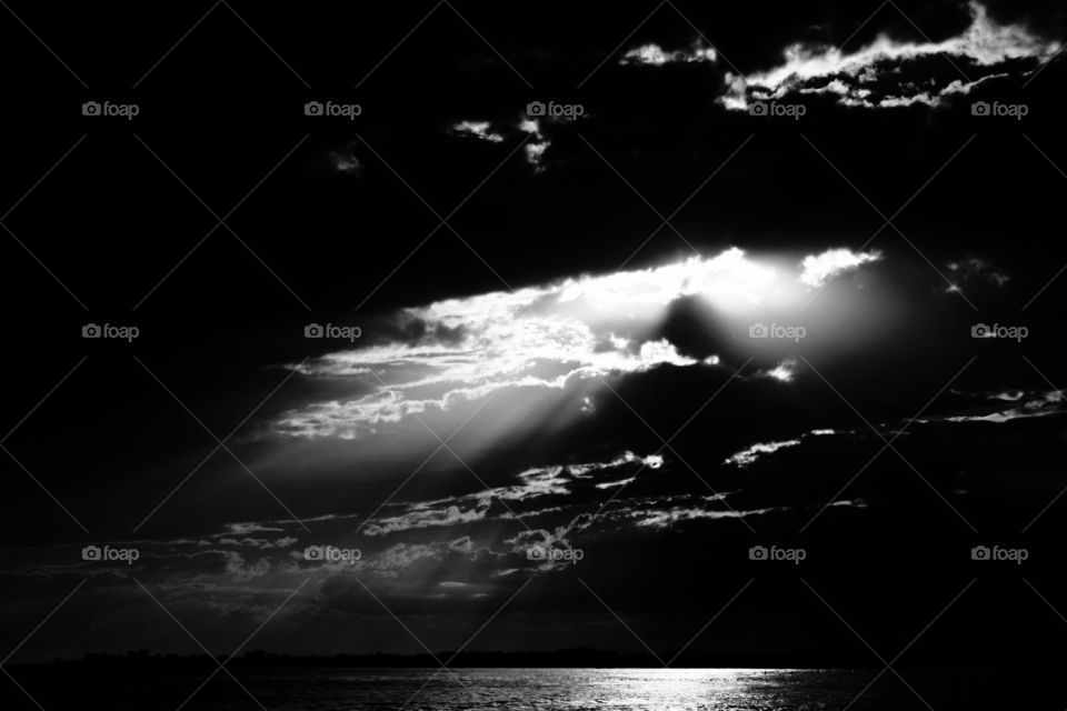 Black and white capture of a cloudy sky above the sea. Violent contrasts. A metaphor of the struggle of the human soul.