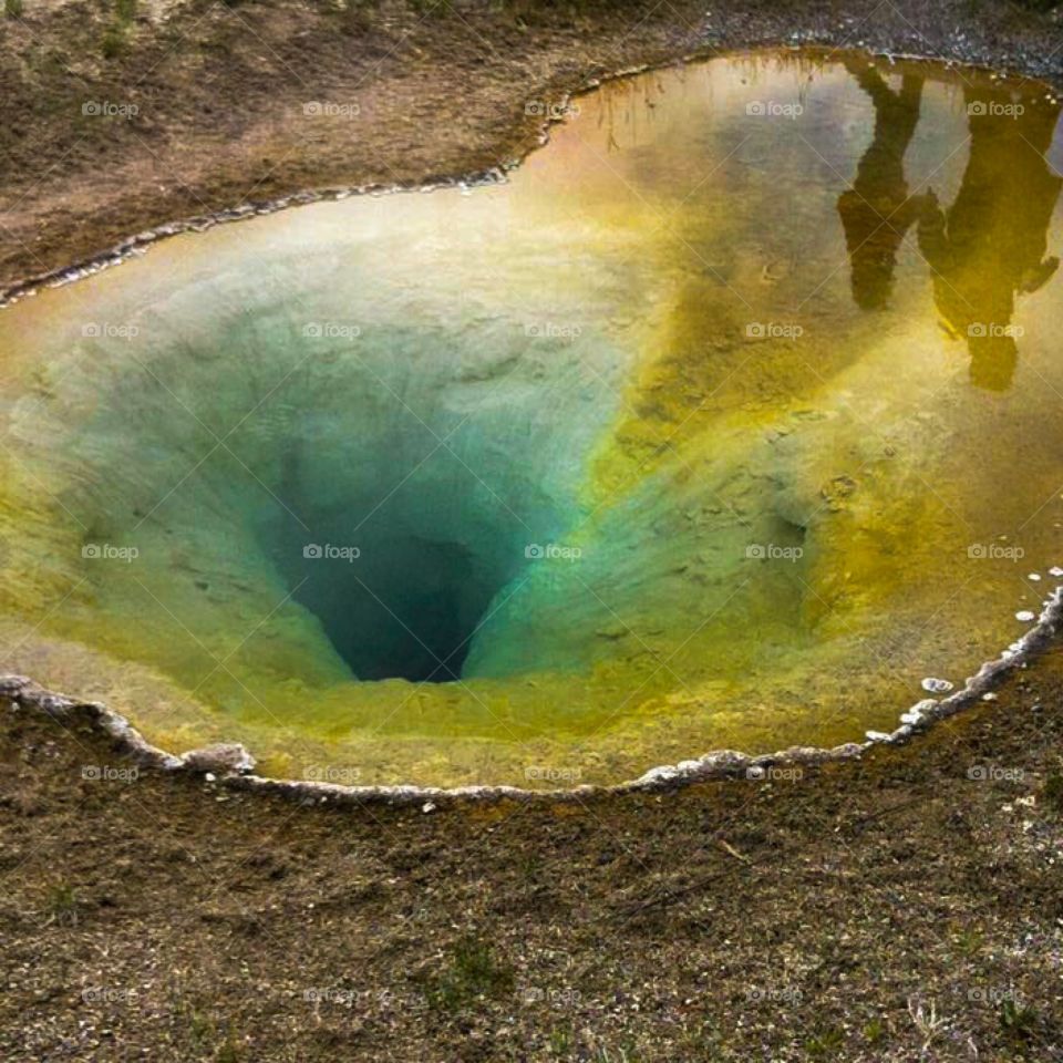 This photo was taken at Yellowstone National Park. There is a reflection in the water. 