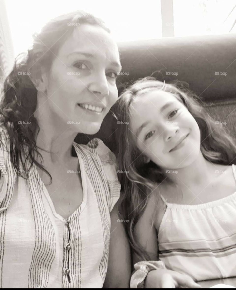 Mother and daughter at home on the couch. looking into the camera