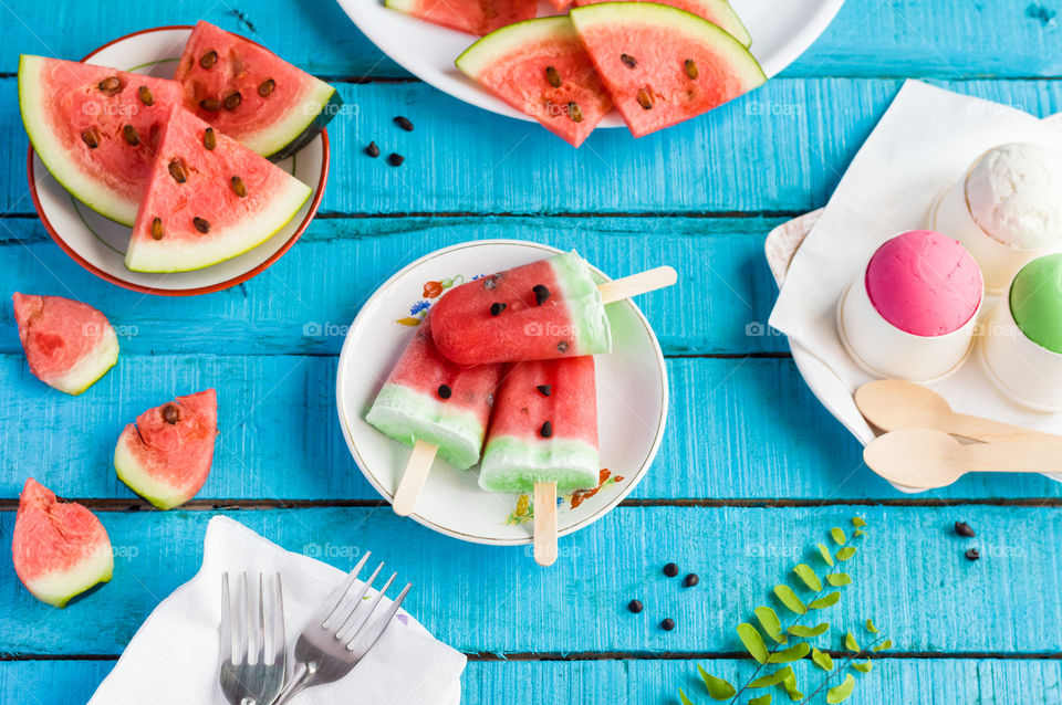 Flatlay of layered watermelon popsicles with watermelon slices and ice creams.Summer refreshment background.