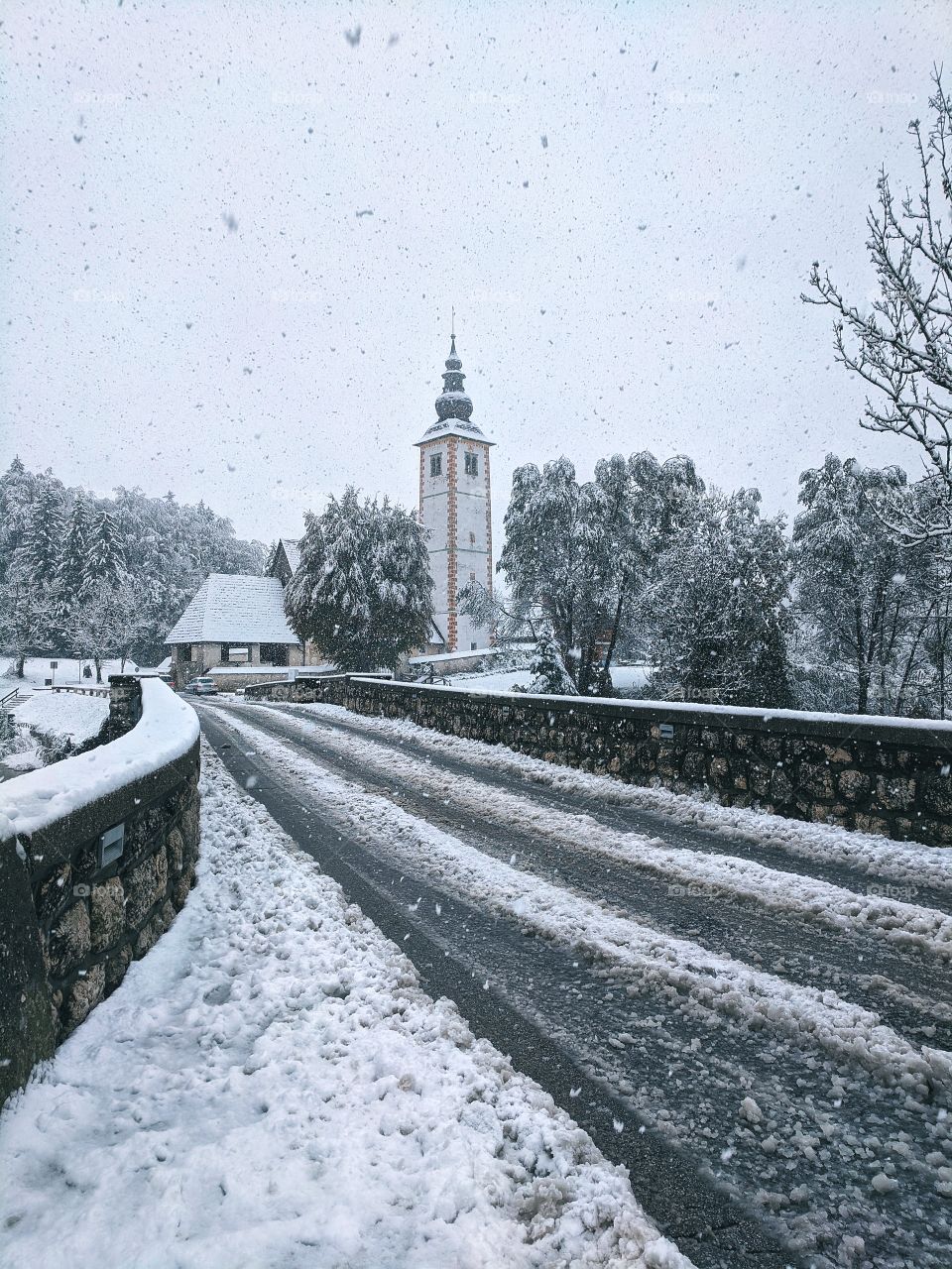 View of snowfall over the river and snow-covered Christmas trees in winter