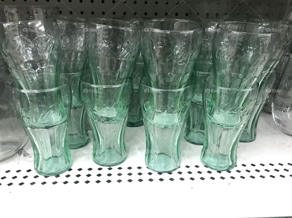 Coca-Cola glass cups displayed on the store shelf located in USA, America. Coke products.