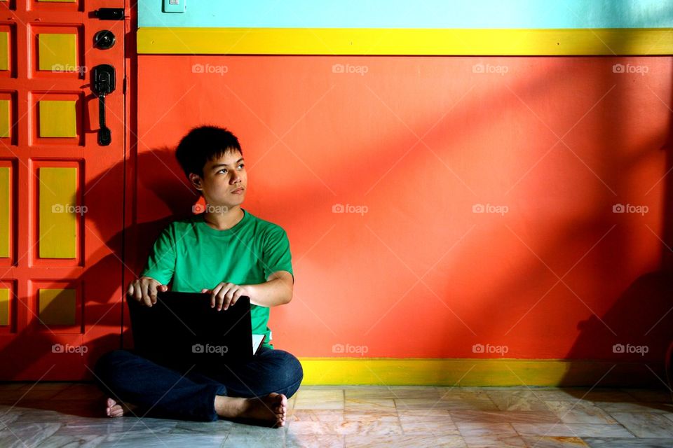 young asian teen with a laptop computer in a living room