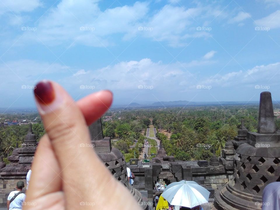 Brown painted nails, crossed love symbol shapes, beautiful temple, sky and mountains background