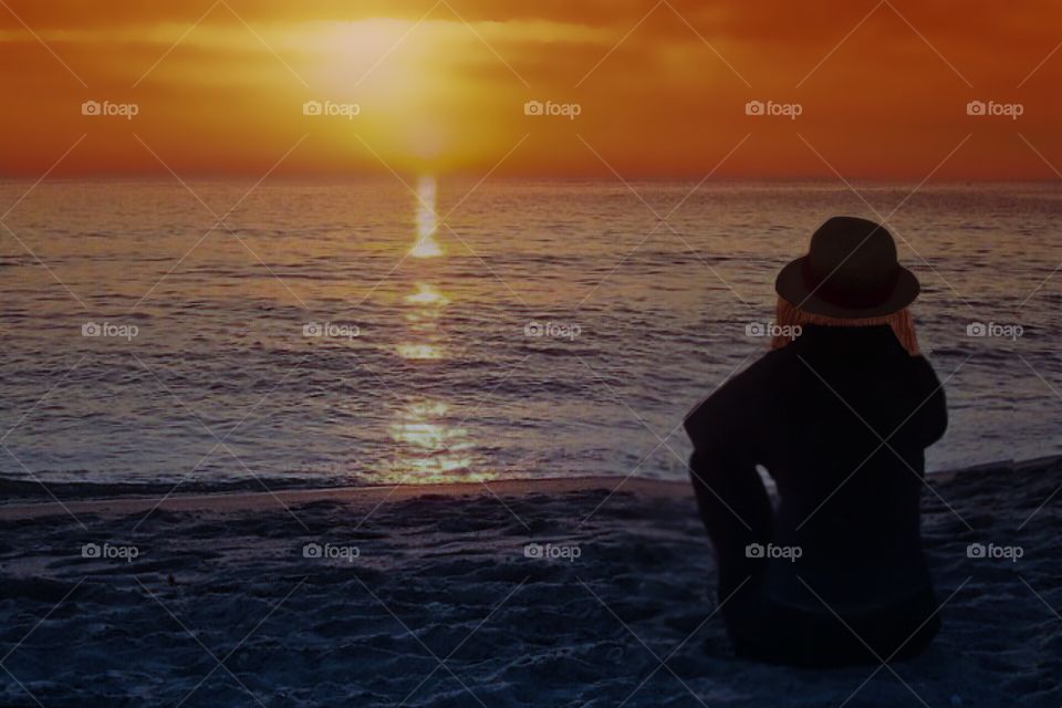 Woman watching a beach sunset on the last days of summer.