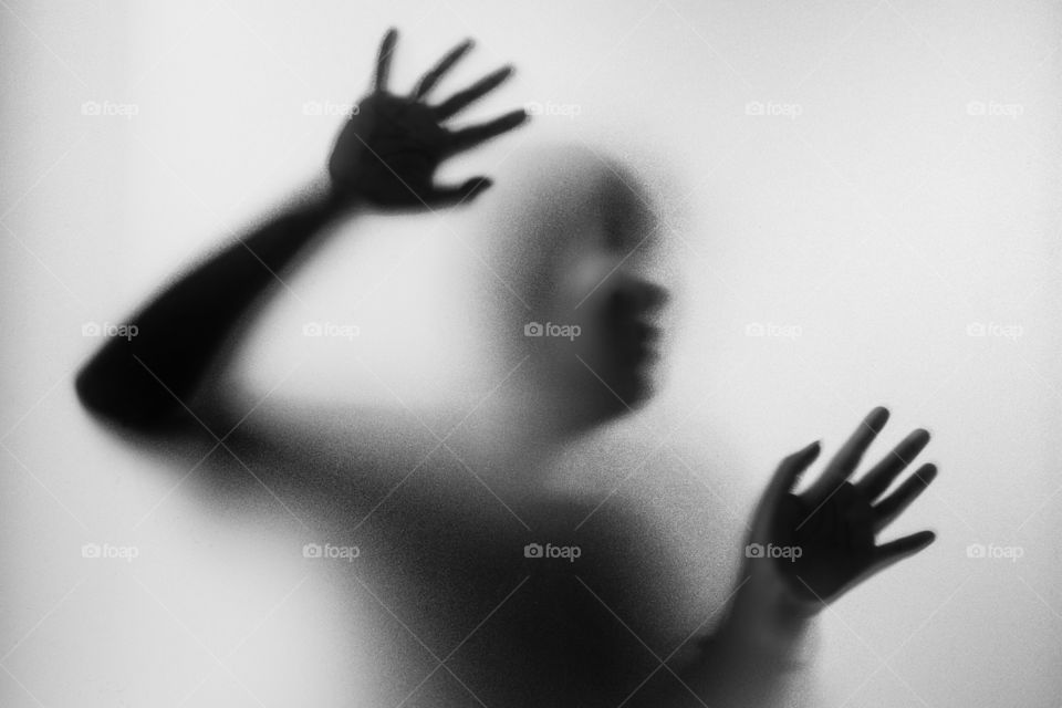 Horror woman behind the matte glass in black and white. Blurry hand and body figure abstraction.Halloween background.Black and white picture