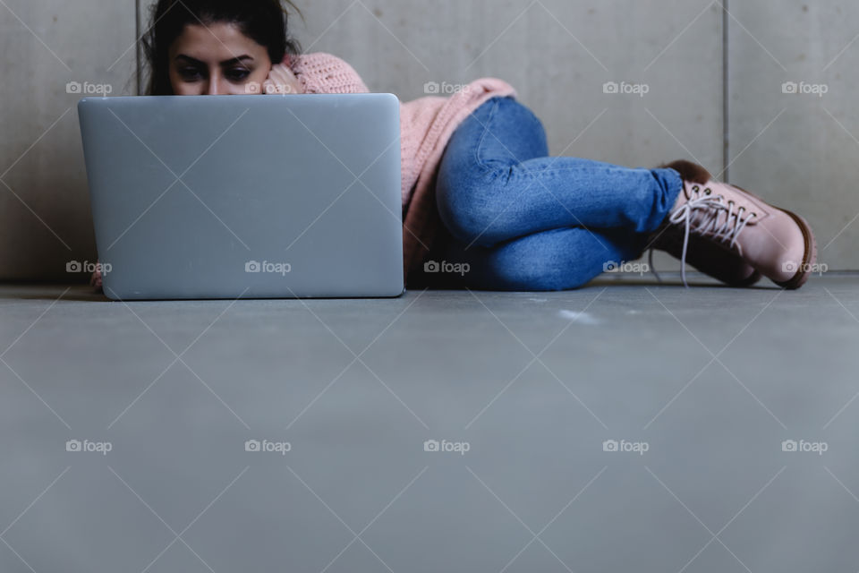 A female laying on floor and using laptop 