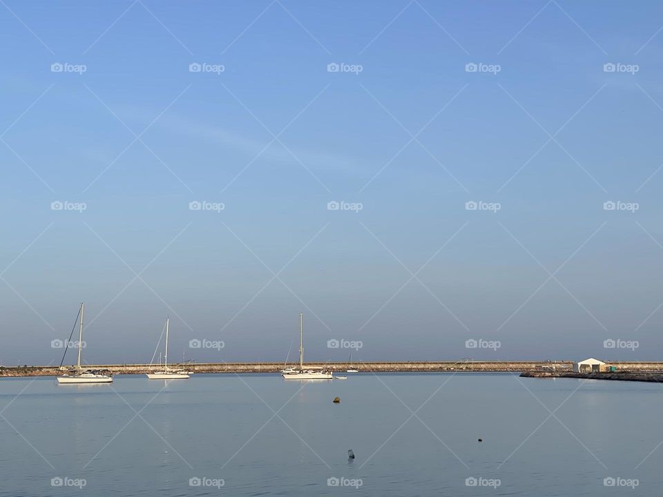 white sailboats on the horizon, sea and blue sky