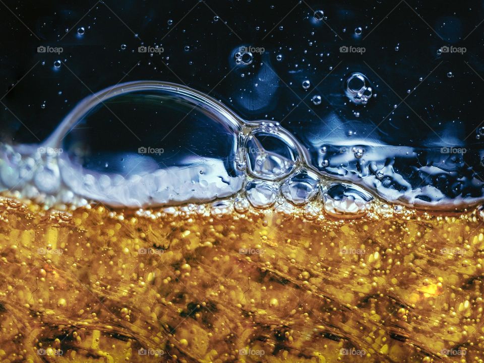 Close up view of yellow washing liquid bubbles in a glass bowl