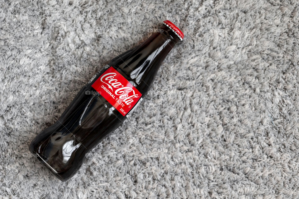 Coca-Cola glass bottle on plush grey soft background