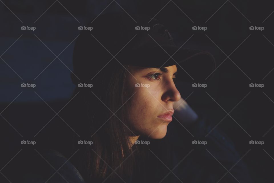 A young woman in sunset rays in a dark room