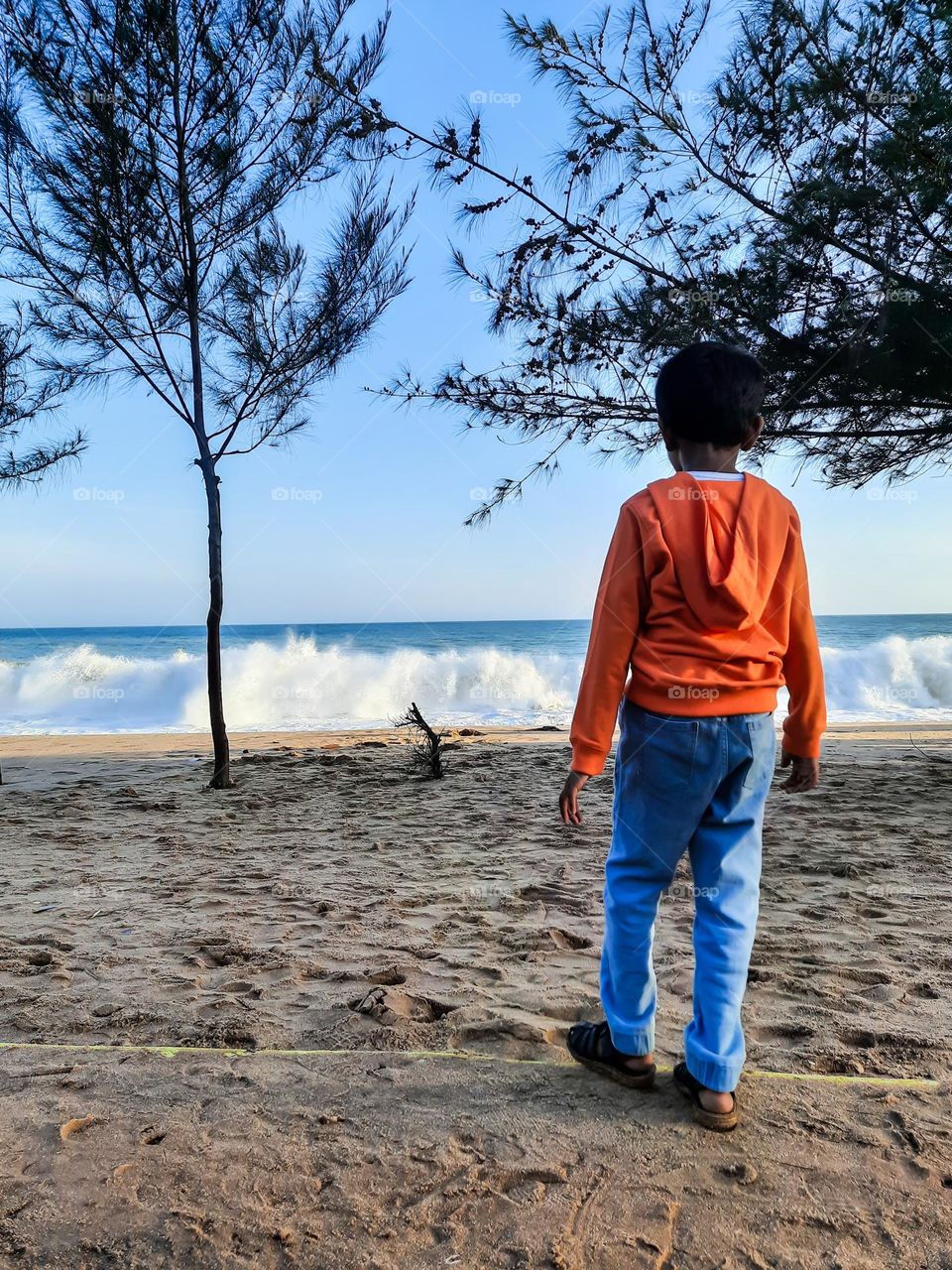 Boy standing and watching the waves of the sea