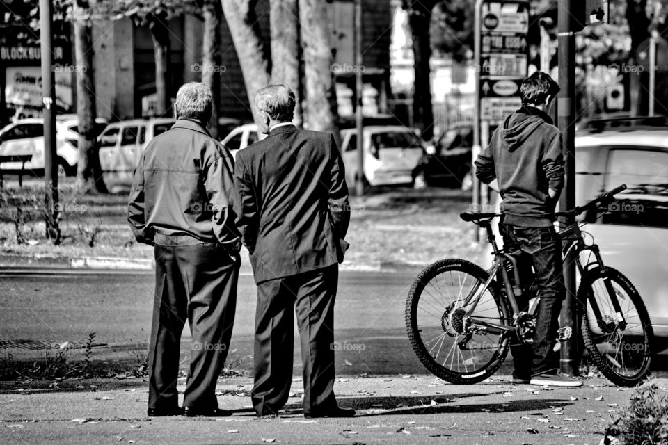 a pair of old men talk standing on the sidewalk