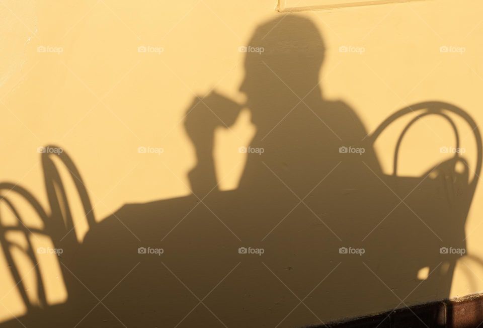 The warm sunrise creates a shadow of a person drinking morning coffee.
