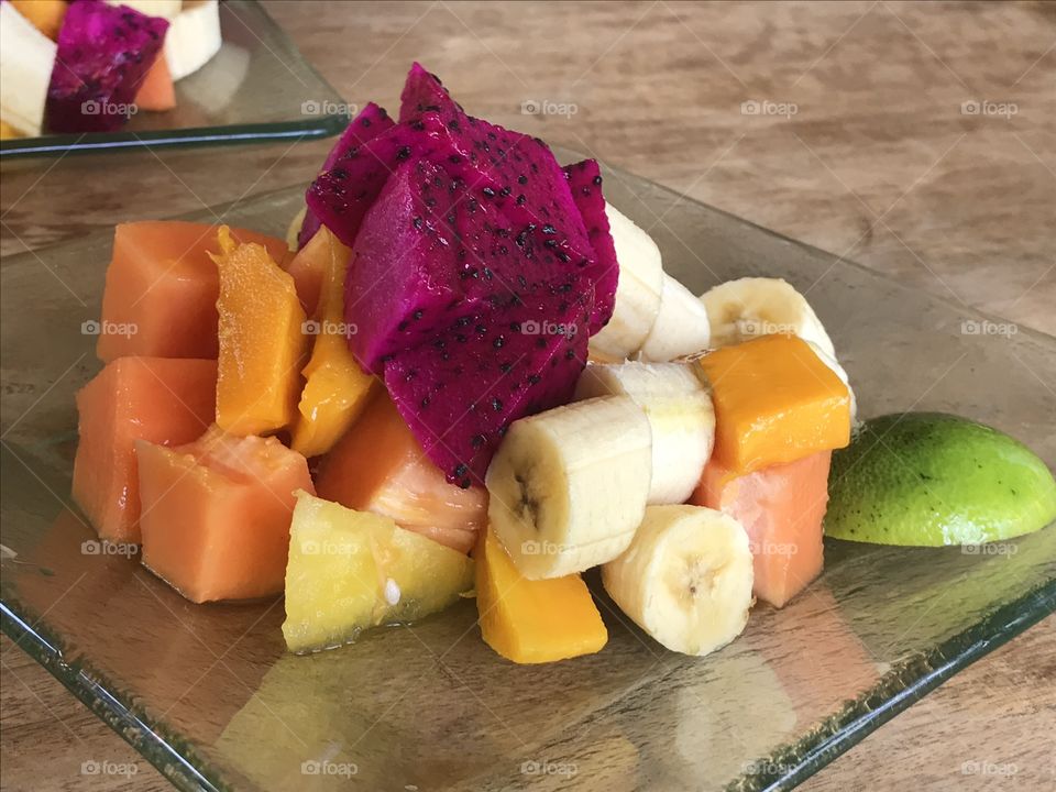 Freshly prepared fruit salad sits on a table in a home in Bali, Indonesia. The salad includes mango, papaya, banana, yellow watermelon, and the bright pink dragonfruit.