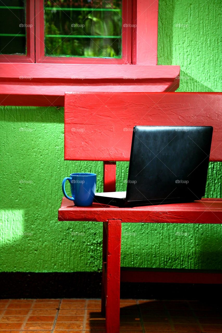 coffee mug and laptop computer on an outdoor bench