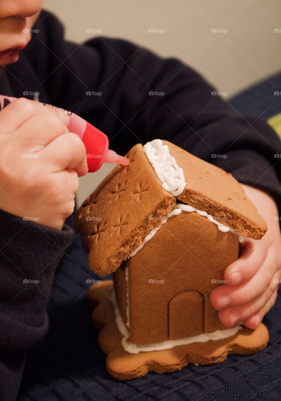 Little boy decorating a gingerbread house 